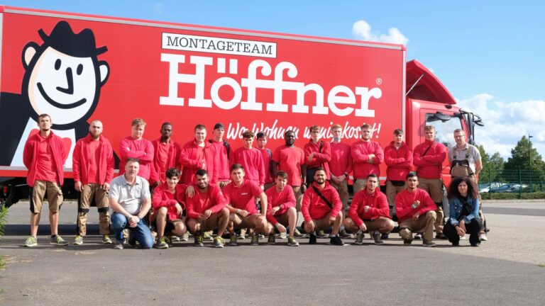 Gruppenbild der Auszubildenden vor einem Möbelwagen